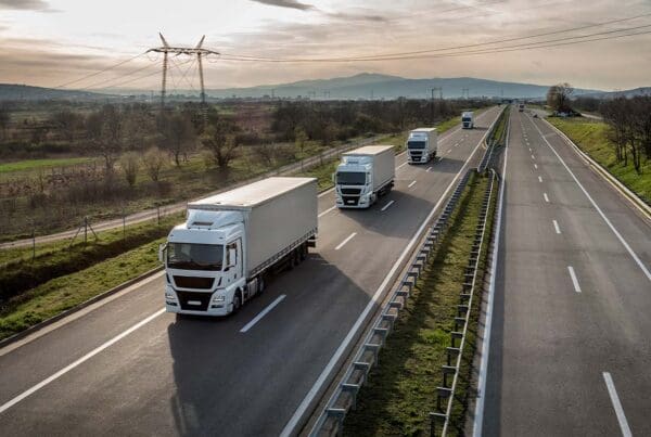 Transportation Insurance - Caravan or Convoy of a Fleet of Semi Trucks in a Line Along a Country Highway on Their Way to Deliver Goods at Dusk